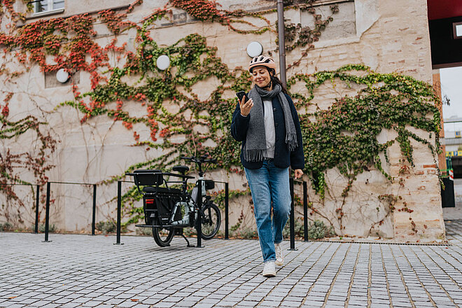 Abgeschlossenes E-Bike und Besitzerin mit Smartphone.