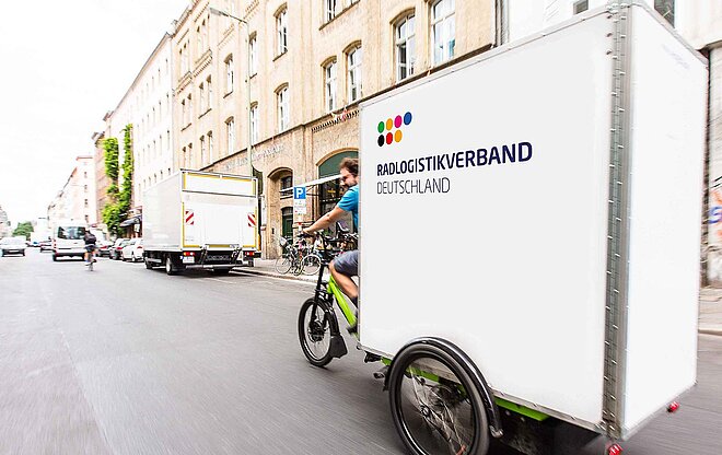 Ein grosses Lastenvelo fährt durch eine Strasse.