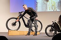 Bosch präsentiert an der Eurobike die neue Generation des Smart System. Ein Mann steht vor einem E-Mountainbike. 