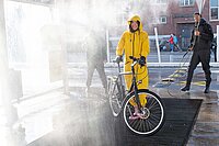 Eine Frau im gelben Overall wird mit Wasser bespritzt