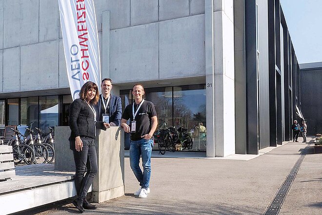 «Schweizer Velo»: Samuel Böhni von der Fachhochschule OST (Mitte), Alexandra Komenda und Reto Meyer von TdS Rad. Zwei Männer und eine Frau stehen vor einem grauen Haus