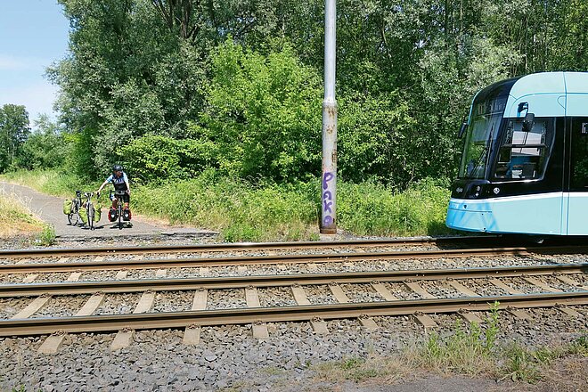 Fahrradreise vier Länder Mitteleuropa. Ein Mann wartet mit dem Fahrrad vor einem Bahnübergang. 