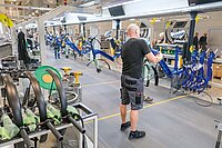 Ein Mann in kurzen Hosen und T-Shirt arbeitet an einem Fahrrad.