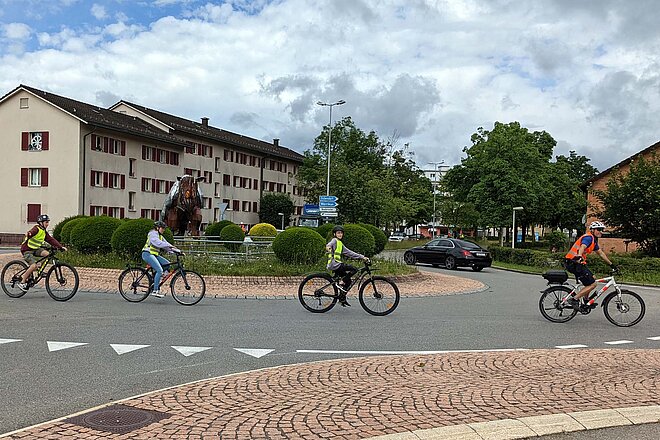 Jugendliche fahren mit Velos durch einen Kreisverkehr.