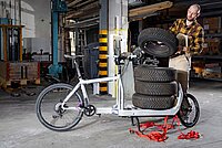 Cargobikes im professionellen Einsatz. Ein Mann lädet Autoersatzreifen auf ein Lastenrad.