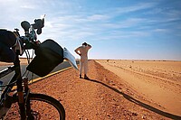 Eine Person steht mit dem Fahrrad in der Wüste