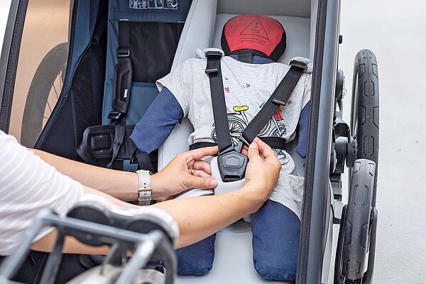 Eine Puppe in einem Kindernanhänger.