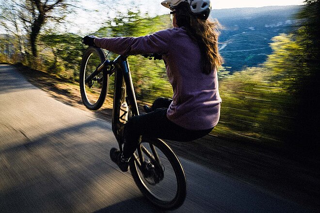 Canyon Preissenkung Schweiz 2025. Eine Frau macht einen Wheelie mit dem Mountainbike.