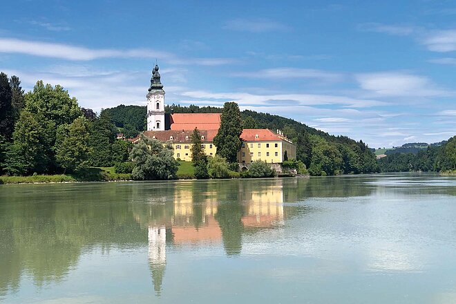Das ehemalige Benediktinerkloster Vornbach in Niederbayern, wenige Kilometer vor der Mündung des Inn in die Donau. Fahrradreise Inn-Radweg mit E-Bike. Kirche am Wasser.