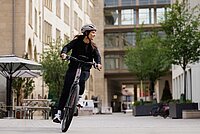 Bosch Smart System KI Neue Features. Eine junge Frau fährt auf einem E-Bike durch die Stadt. 