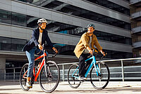 Shimano Cues Update. Zwei Personen fahren auf Rennrädern durch die Stadt.