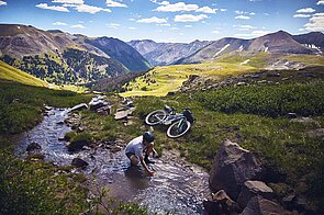 Eine Person füllt eine Flasche in einem Bergbach.
