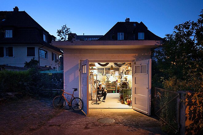 Ein Mann arbeitet in einer Garagenbox an einem Fahrrad.