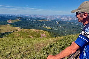 Ein Mann mit Fahrradtricot blickt von einem Aussichtspunkt ins Tal.