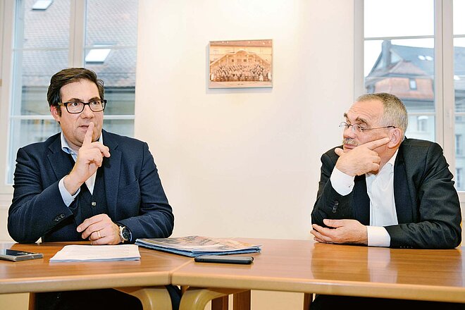 Pro und Kontra Veloweggesetz. Zwei Männer im Anzug sitzen an einem Besprechungstisch..