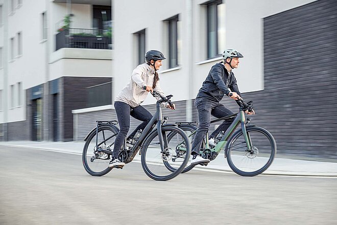 Zwei Personen auf einem E-Bike.