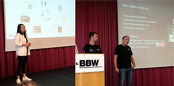 Eine Frau und zwei Männer stehen auf einer Bühne und halten eine Präsentation.