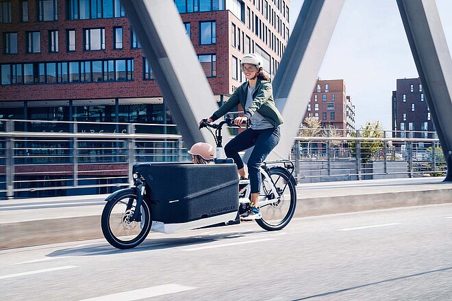 E-Bikes gibt es für jedes Einsatzgebiet. (Foto ZVG) E-Bikes 2023. Die besten Modelle des Jahres. Eine Frau transportiert ein Kind auf einem Cargobike von Riese & Müller.