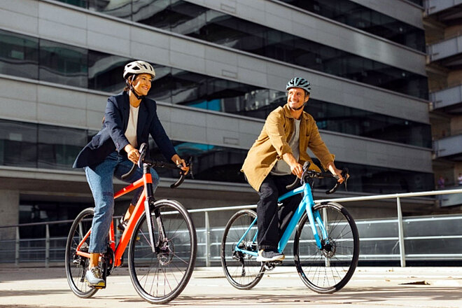 Shimano Cues Update. Zwei Personen fahren auf Rennrädern durch die Stadt.