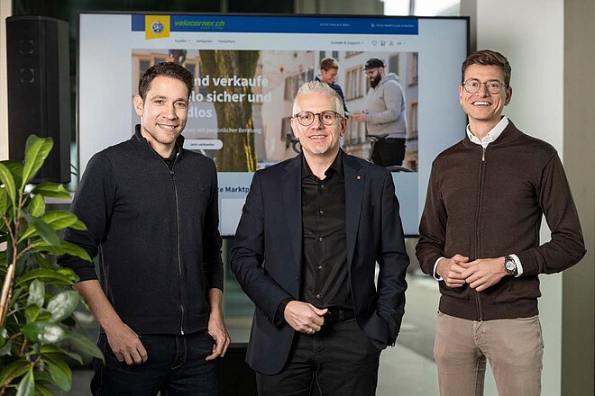 TCS übernimmt Velocorner. Drei Männer posieren für ein Foto. 