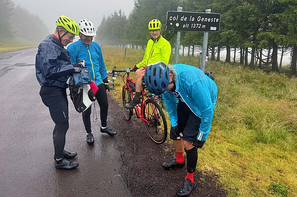 Radfahrer stehen im Regen am Strassenrand.
