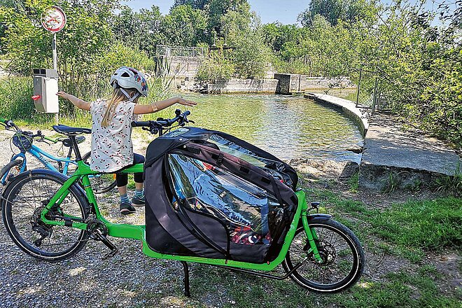 Locker durch die Schweiz radeln: Vier Routen zwischen Bodensee und Genfersee. Ein Kind sitzt auf einen grünen Cargobike.