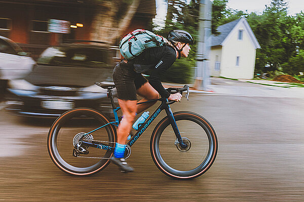 Mondraker Arid Carbon. Eine Frau mit Bib-Shorts fährt auf einem Gravelbike in der Stadt.