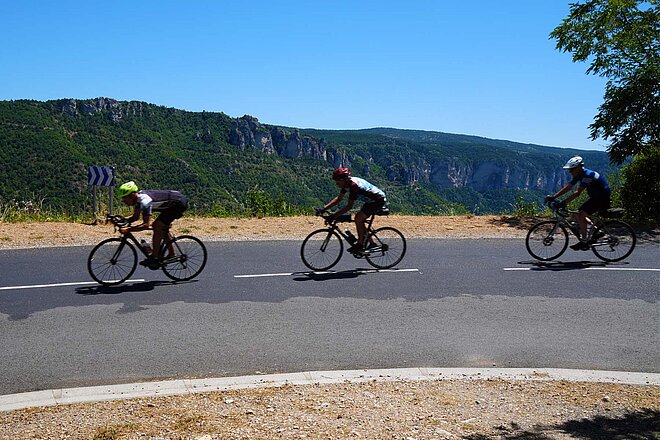 Radfahrer fahren hintereinander eine Strasse hinunter. 