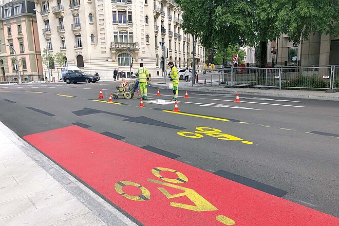 Arbeiter bringen auf einer Strasse in Genf Velowegmarkierungen an