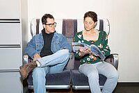 Ein Mann und eine Frau sitzen auf Zugsesseln in einem Büro.