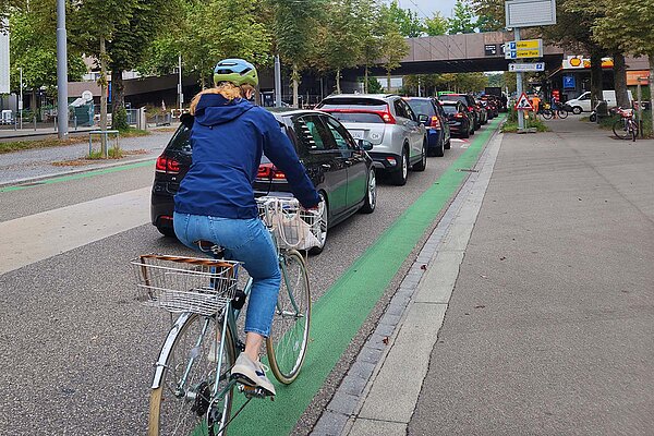 Eine Radfahrerin fährt auf einer Strasse mit vielen Autos in Zürich.