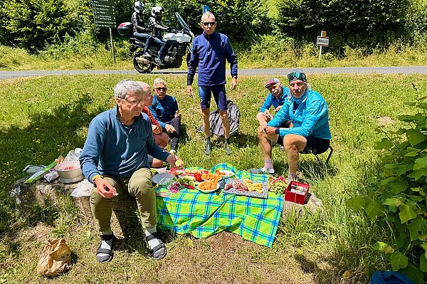 Männer sitzen auf einer Picknickdecke. 