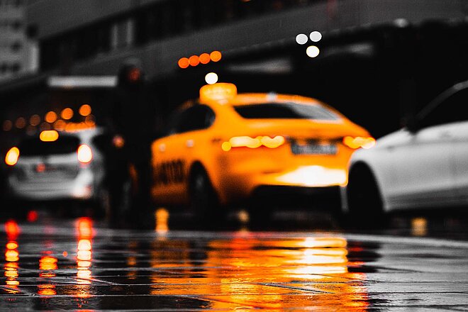 Mit dem Taxi durch Wien. Autos spiegeln sich auf dem nassen Asphalt.