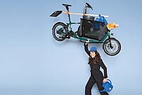 Eine Frau hebt ein Fahrrad in die Luft