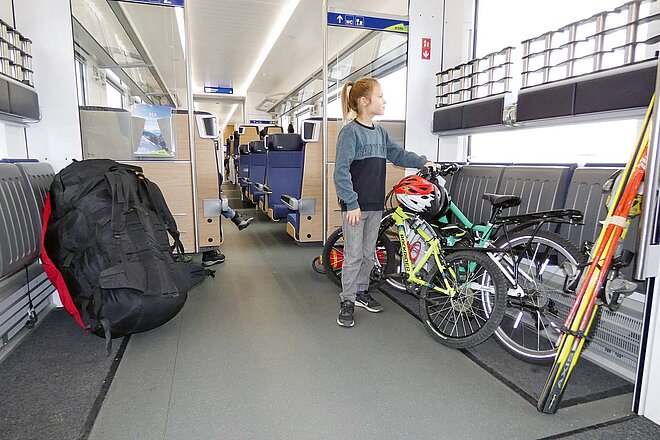 Kindervelos reisen im öffentlichen Verkehr gratis, wenn eine erwachsene Person mitfährt. Auf die neue Saison hin können Velofahrende von etlichen Verbesserungen beim Veloverlad profitieren. Ein Kind steht neben einem Fahrrad in einem Zugabteil.