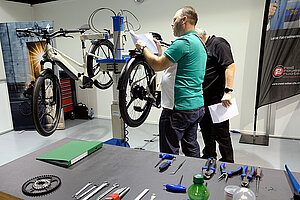 Die Schweizer Velomechaniker brillieren. Zwei Männer arbeiten an einem Fahrrad. 