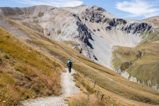 Eine Bikerin fährt durch die Berglandschaft.