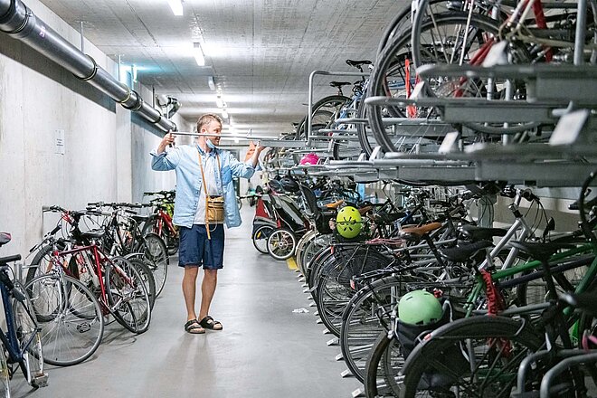 Ein Mann nimmt sein Fahrrad aus einem Fahrradkeller.